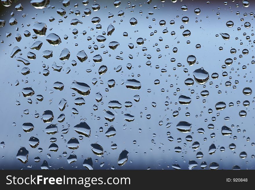 Raindrops at a window - blue background. Raindrops at a window - blue background