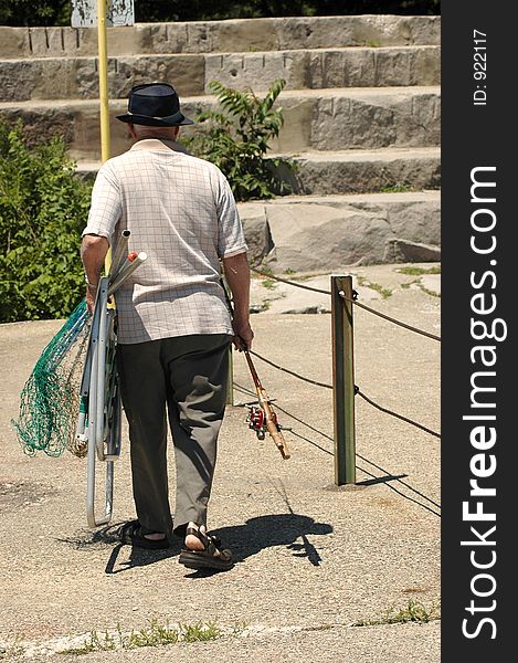 Elderly man leaving after fishing. Elderly man leaving after fishing