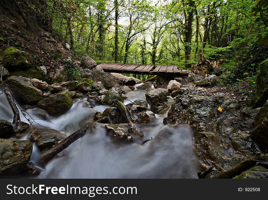 A small wooden bridge across a mountain torrent. A small wooden bridge across a mountain torrent