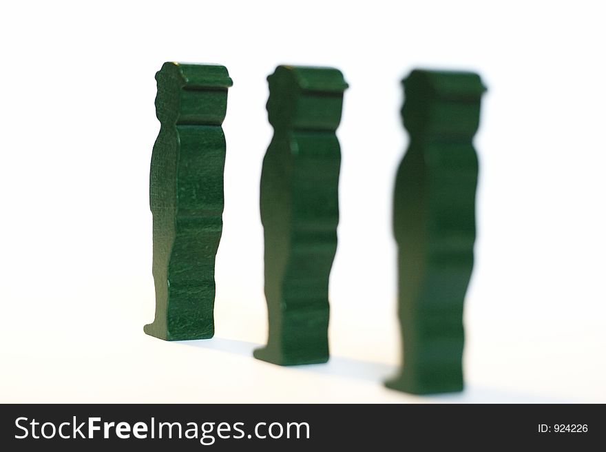 Three green wooden men on a white background. Waiting in line or something. Three green wooden men on a white background. Waiting in line or something.