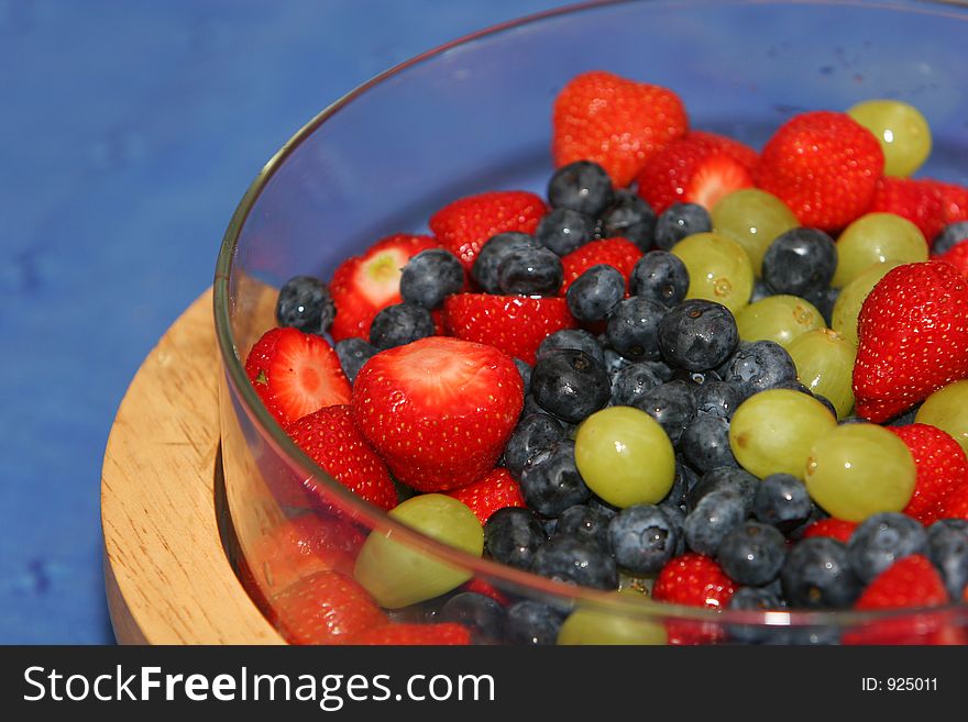 A dish of fresh berries, strawberries, blueberries, grapes and whipped cream. A dish of fresh berries, strawberries, blueberries, grapes and whipped cream.