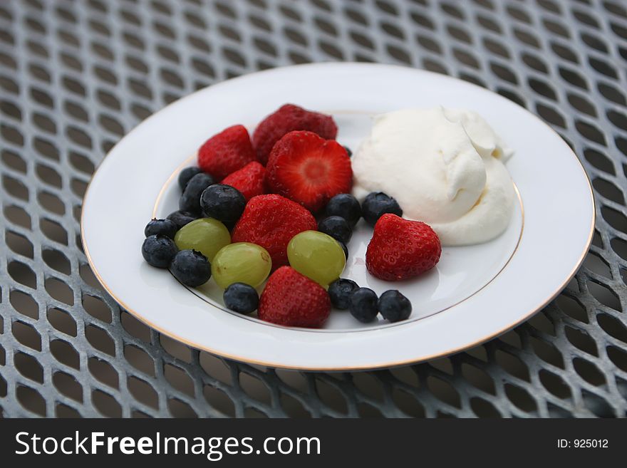 A dish of fresh berries, strawberries, blueberries, grapes and whipped cream. A dish of fresh berries, strawberries, blueberries, grapes and whipped cream.