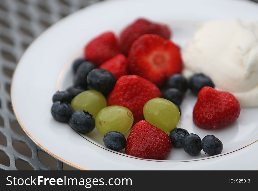 A dish of fresh berries, strawberries, blueberries, grapes and whipped cream. A dish of fresh berries, strawberries, blueberries, grapes and whipped cream.
