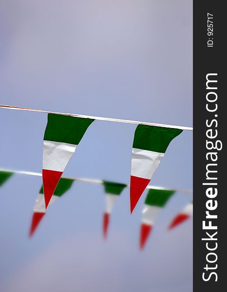 Some small Italian flags on a blue sky background, short depth of field, first row in focus and second row blurred