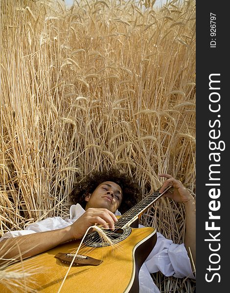 Cool guy laying in a cornfield playing guitar. Cool guy laying in a cornfield playing guitar