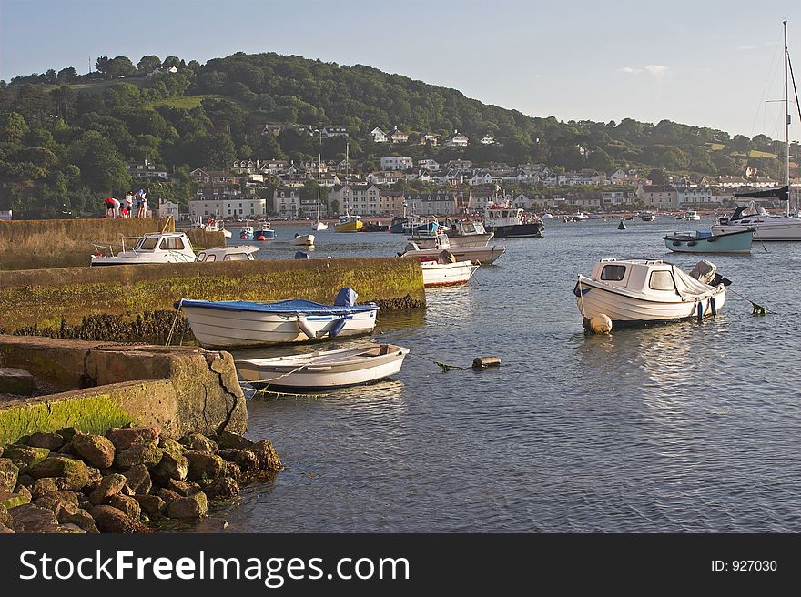 Boats moored in harbour with coastal village in background. Boats moored in harbour with coastal village in background