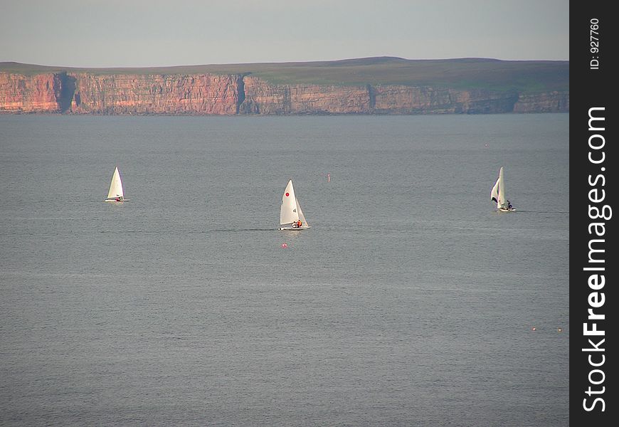 Three of the sailing club enjoying a sunday afternoon in Thurso Bay with the sun on the red cliffs of Dunnet Head.