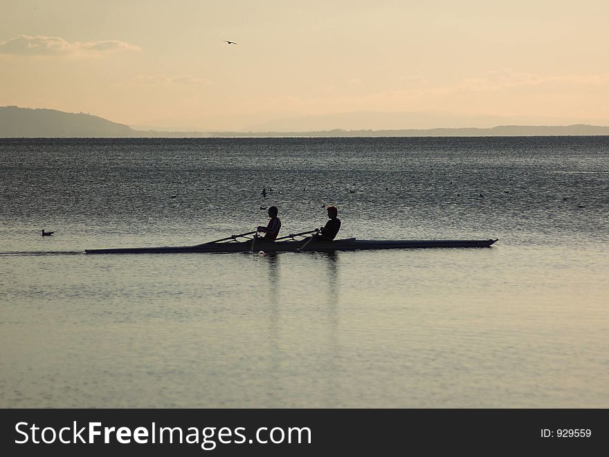 Two rowers silhouetted at dusk on a lake. Two rowers silhouetted at dusk on a lake