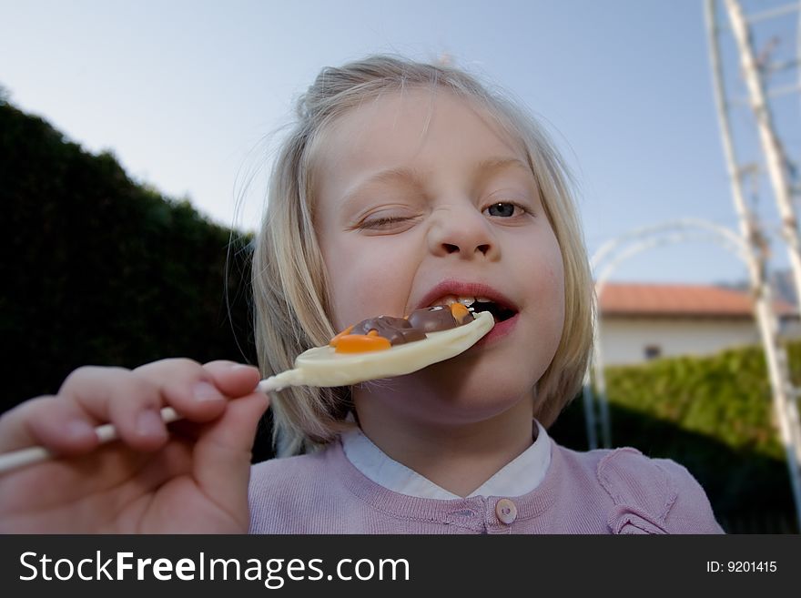 Young girl eating a chocolate lollipop