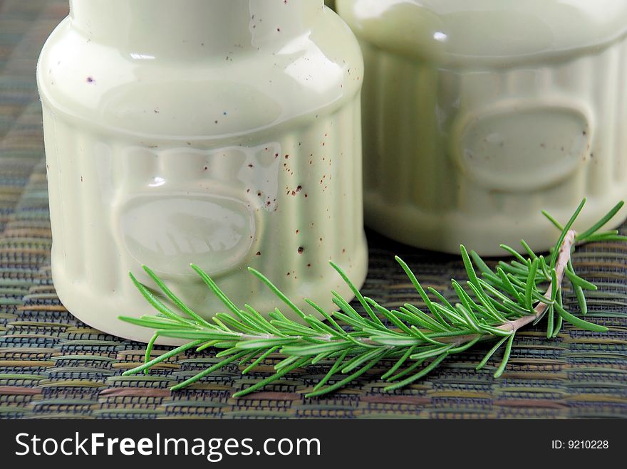 A sprig of fresh rosemary in the kitchen with two antique jars.