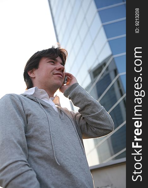 A man talking on a cell phone against the backdrop of a modern building. A man talking on a cell phone against the backdrop of a modern building