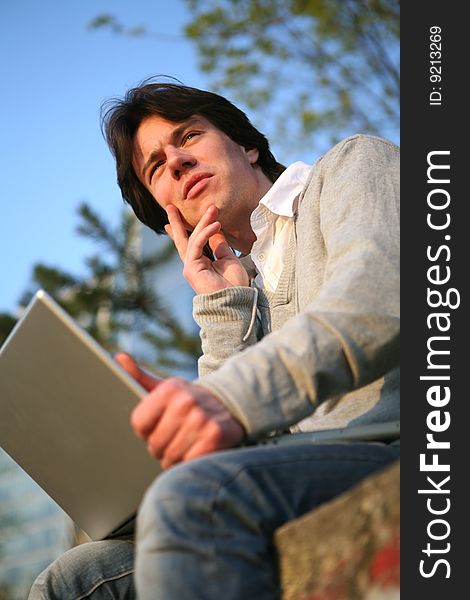 Young man working on a laptop outside. Young man working on a laptop outside.