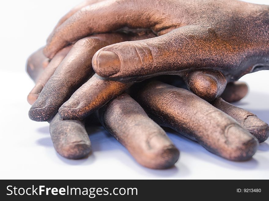 A sculpture of three bronzed hands stacked in a pile. A sculpture of three bronzed hands stacked in a pile