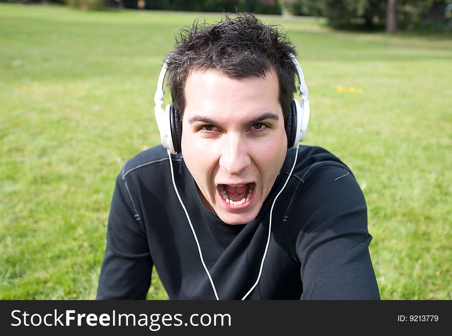 Man screaming his frustration in the middle of a green area. Man screaming his frustration in the middle of a green area