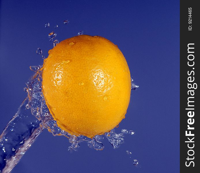 Water splashing against a lemon on the violet background. Water splashing against a lemon on the violet background