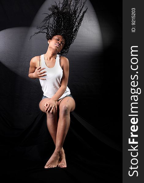 Wind - lovely young afro-american woman with long flapping hairs against black background