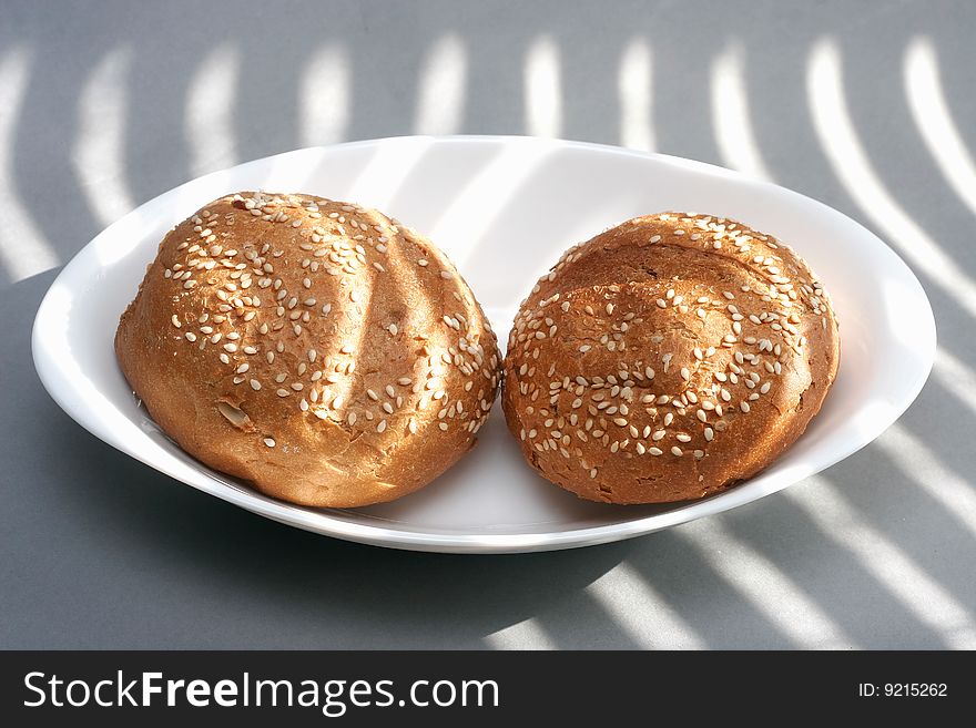 Two loafs, sesam seeds, white plate