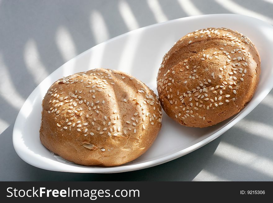 Two loafs, white plate, sesam