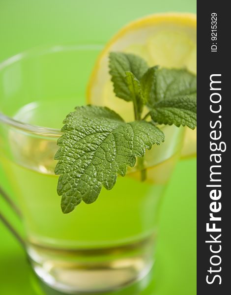 Herb tea with lemon on green table