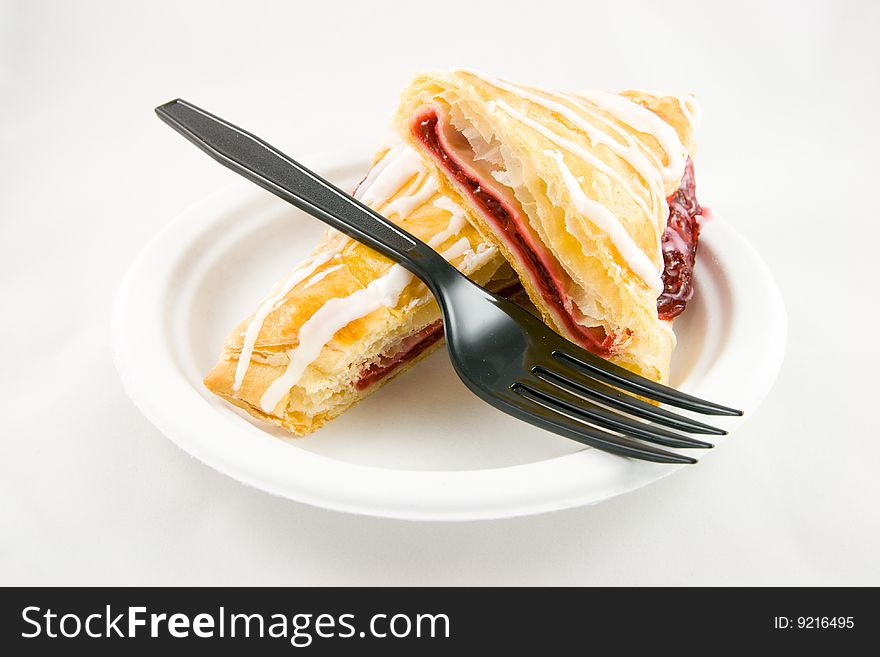 Cherry danish with black fork on a white plate and white background. Cherry danish with black fork on a white plate and white background