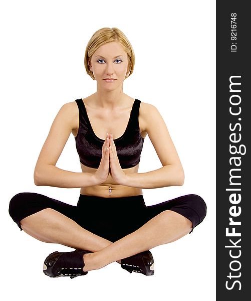 A blond young woman in a fitness outfit is sitting in a lotus position doing yoga. A blond young woman in a fitness outfit is sitting in a lotus position doing yoga