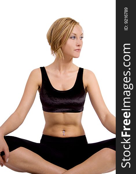 A blond young woman in a fitness outfit is sitting in a lotus position doing yoga. A blond young woman in a fitness outfit is sitting in a lotus position doing yoga