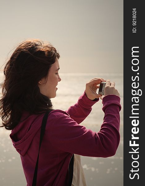 Teen girl taking photos on the beach