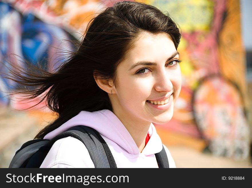 Pretty teenage girl sitting by the wall with graffiti outdoor. Pretty teenage girl sitting by the wall with graffiti outdoor