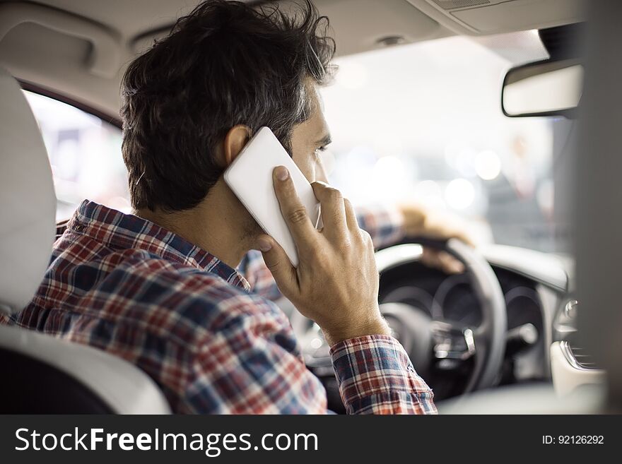 View at young handsome man driving modern car and using mobil phone. View at young handsome man driving modern car and using mobil phone