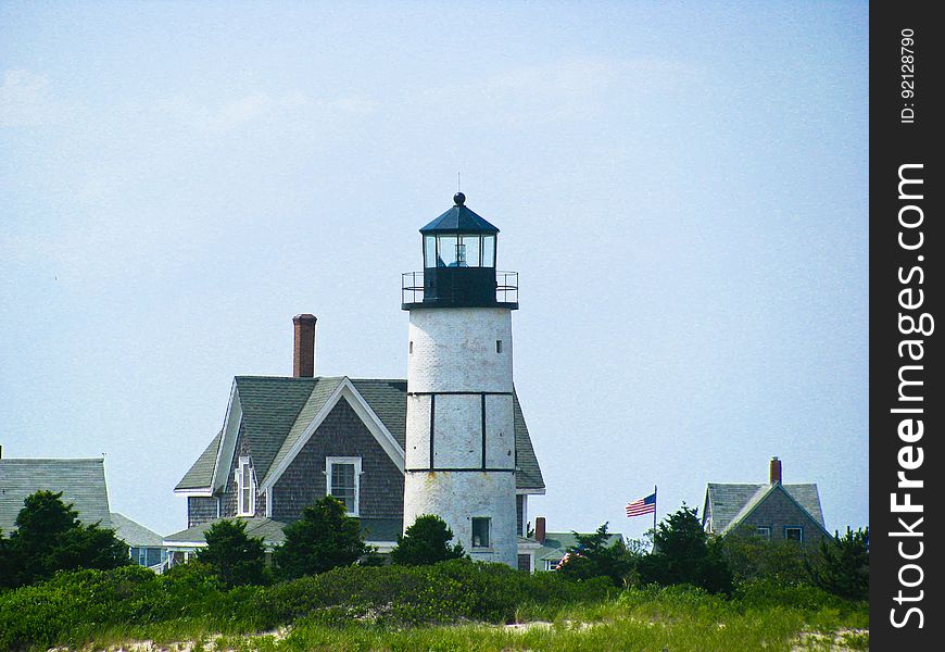 Lighthouse By Home With American Flag