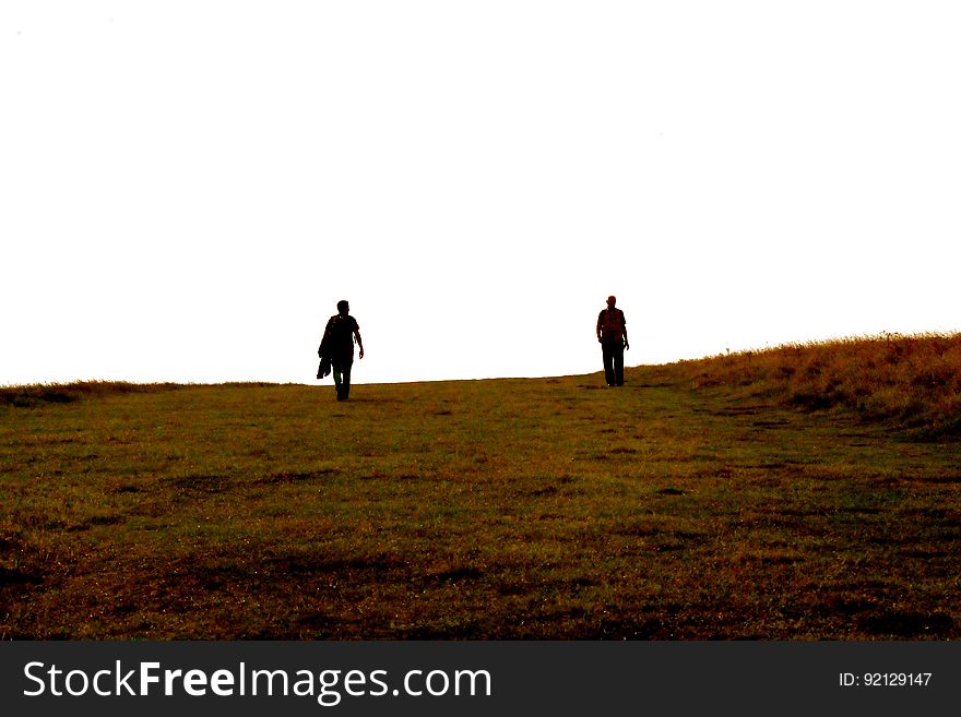 Two People Walking On Barren Landscape
