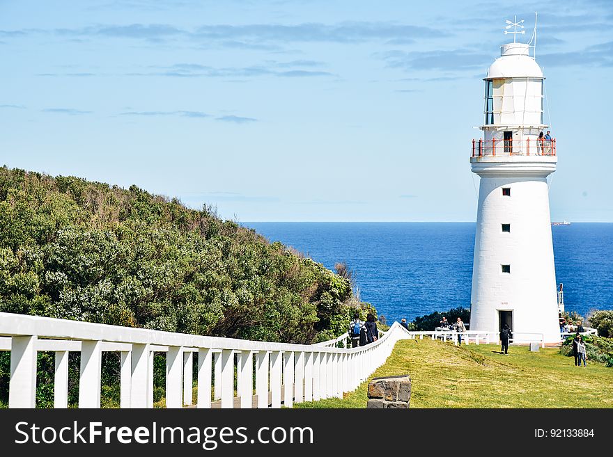 People Standing in Front of White Concrete Lighthouse during Daytime