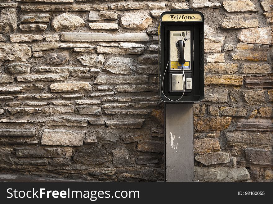 Gray and Black Telephone Booth Standing Near Gray Stone Wall at Daytime