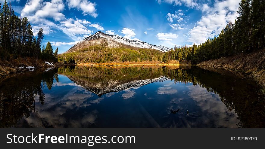 A lake with conifer forest on the shores and a mountain reflecting from the surface. A lake with conifer forest on the shores and a mountain reflecting from the surface.