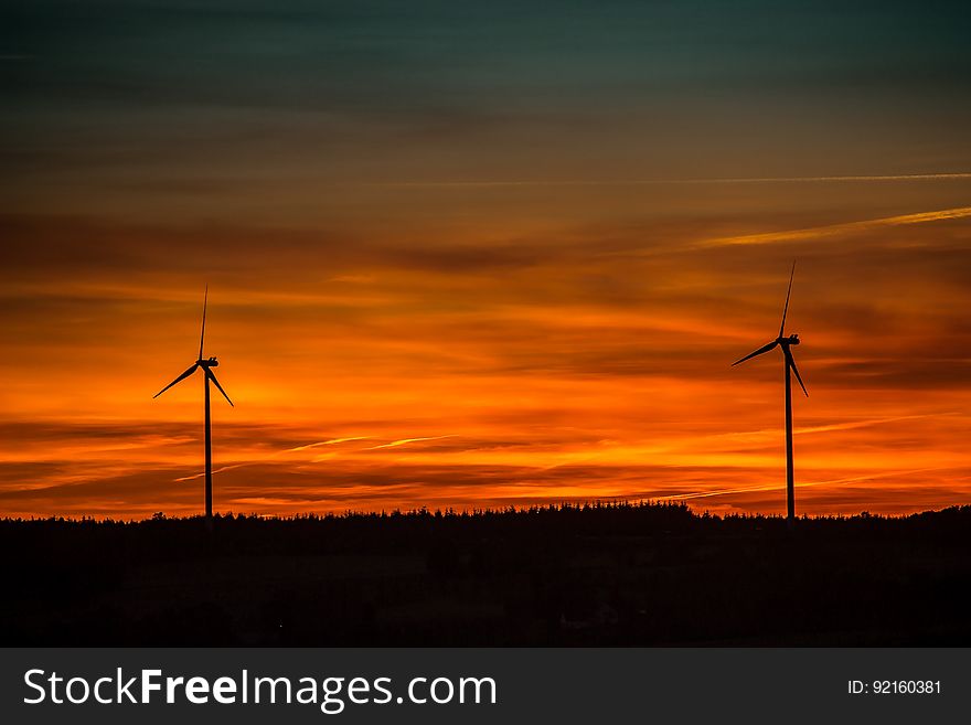 Silhouette of Windmills Under Orange Sunset
