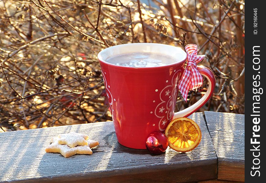 A cup of cocoa and biscuits on a railing on a cold winter day.