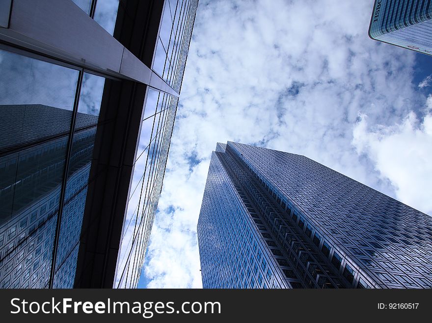 Low angle view looking to top of modern skyscrapers with cloudscape reflecting off glass windows. Low angle view looking to top of modern skyscrapers with cloudscape reflecting off glass windows.