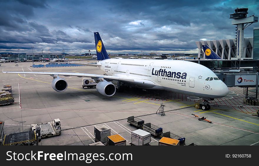 A Lufthansa Airbus A380 with passengers and cargo loading at airport terminal. A Lufthansa Airbus A380 with passengers and cargo loading at airport terminal.