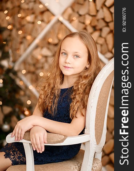 A portrait of a young girl sitting on an antique chair. A portrait of a young girl sitting on an antique chair.