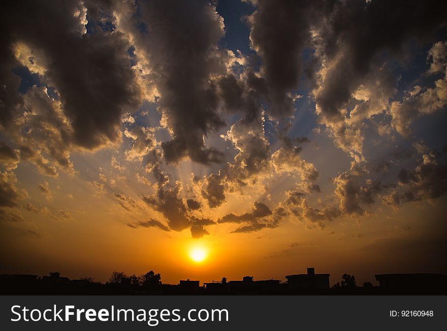 Setting sun in orange skies with grey clouds on horizon. Setting sun in orange skies with grey clouds on horizon.