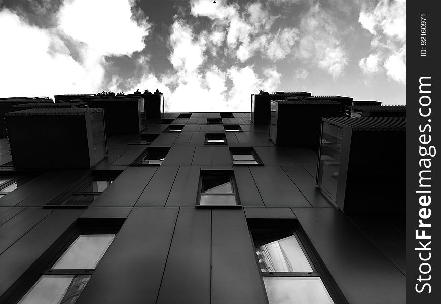Front of modern apartment building with balconies looking to clouds in sky in black and white. Front of modern apartment building with balconies looking to clouds in sky in black and white.