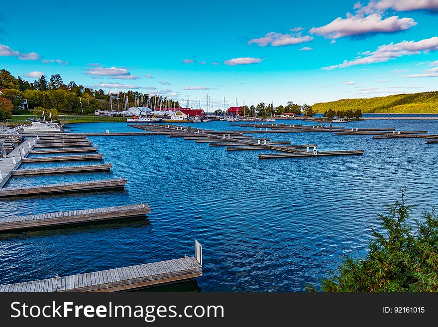 Line of empty wooden docks along waterfront of blue waters against blue skies on sunny day. Line of empty wooden docks along waterfront of blue waters against blue skies on sunny day.
