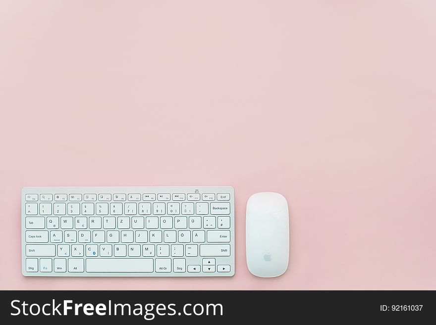 Computer keyboard and mouse with Apple logo on pink. Computer keyboard and mouse with Apple logo on pink.