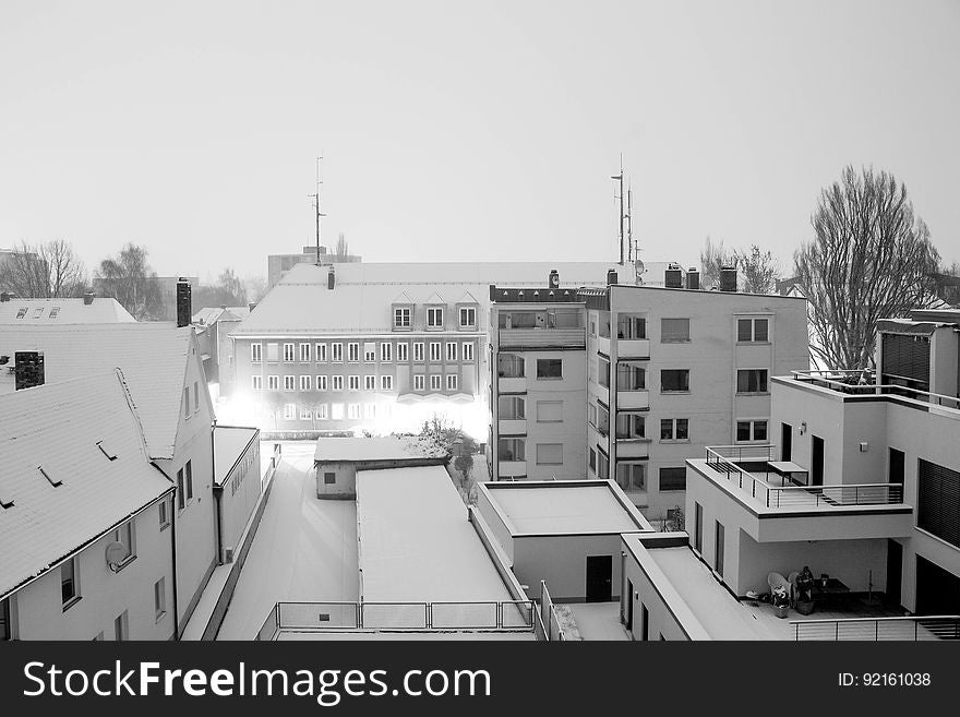 Snow covered urban rooftops with lights in evening in black and white. Snow covered urban rooftops with lights in evening in black and white.