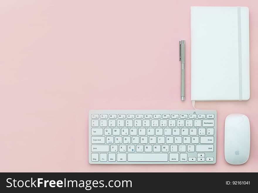 Keyboard and mouse on pink with notepad