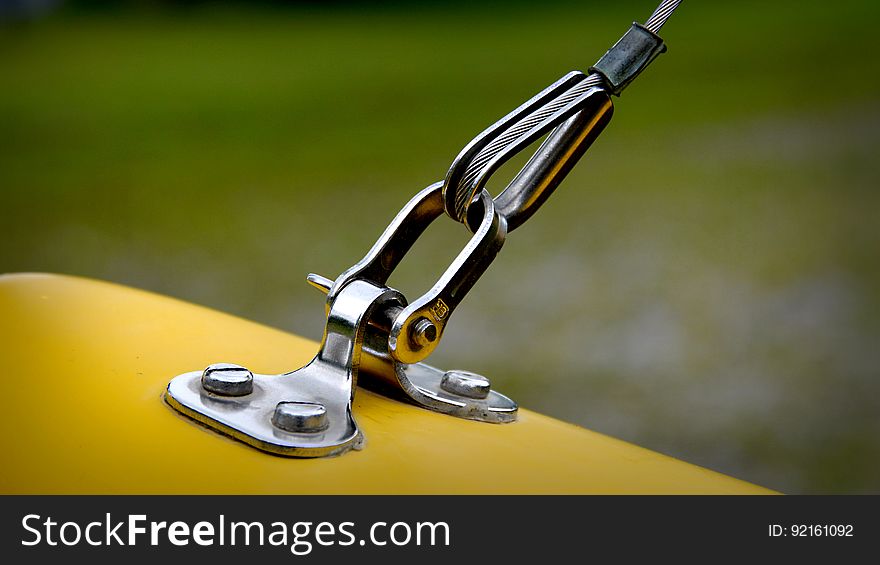 Close up of chrome metal hook and fastener on yellow surface. Close up of chrome metal hook and fastener on yellow surface.