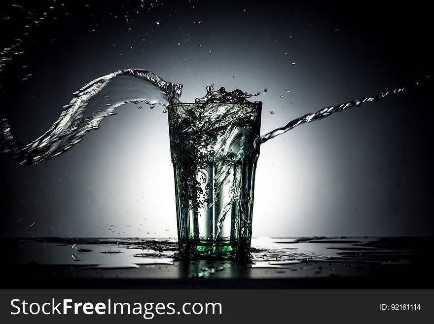 A glass of water with water splashing out of it. A glass of water with water splashing out of it.