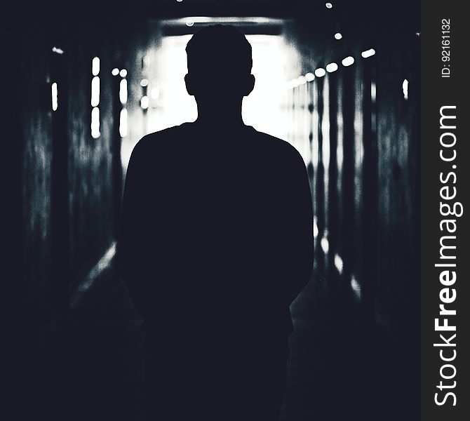 The silhouette of a man standing in a dark tunnel. The silhouette of a man standing in a dark tunnel.