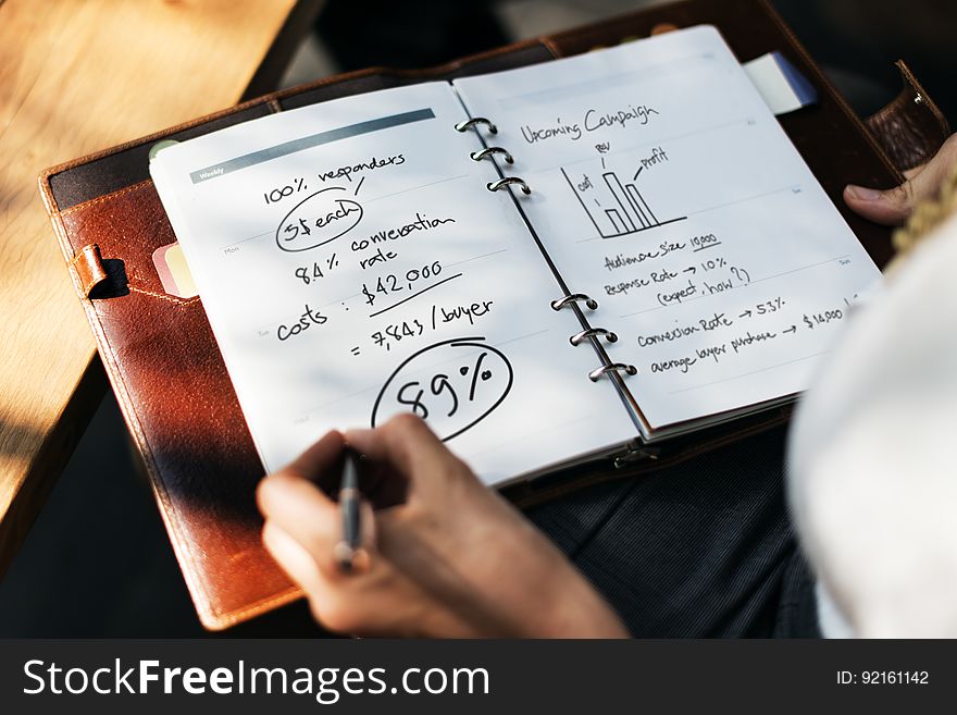 Person Making Financial Calculations In Notebook