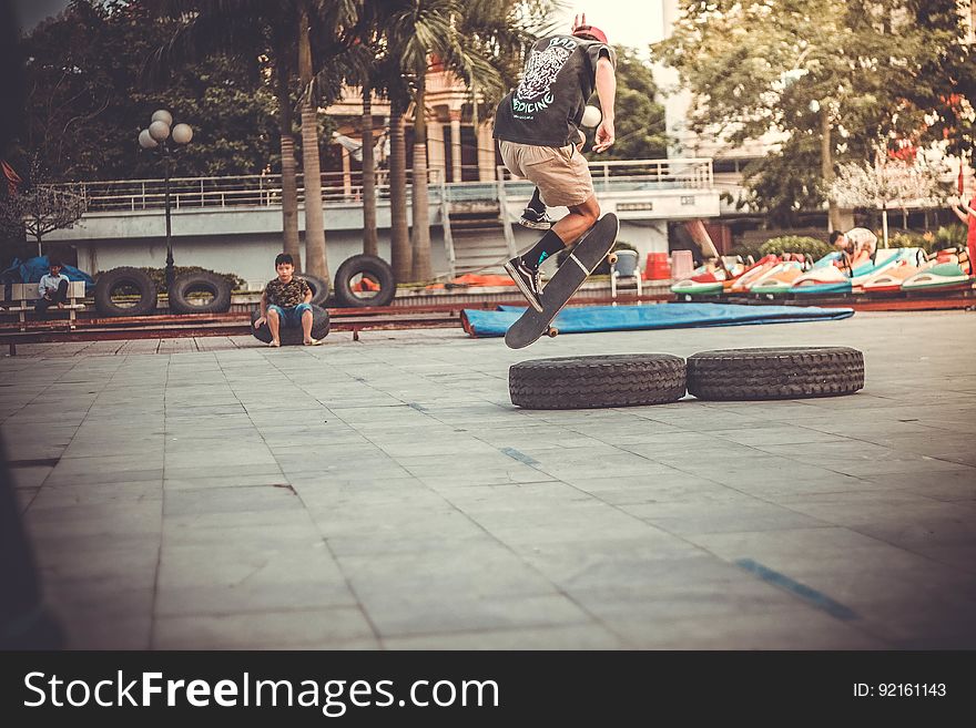 A skateboarder on the street jumping over a pair of tires. A skateboarder on the street jumping over a pair of tires.